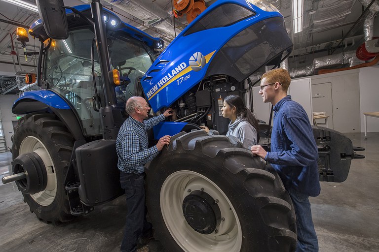 Ag systems management students and professor taking a close look at a New Holland tractor.