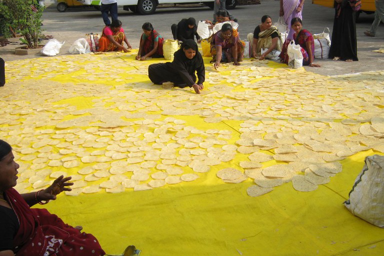 This is a picture from Lijjat Papad. Papad has to be sundried on tarps before the women sort them into stacks for packaging.
