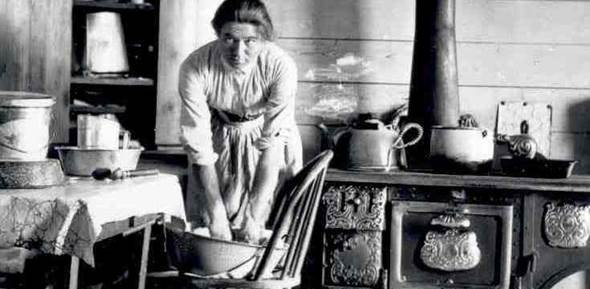 Mrs. Evelyn Cameron kneading dough in her kitchen in Montana.